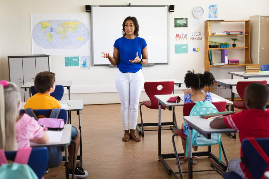 African american female teacher teaching students in the class at elementary school. school and education concept
