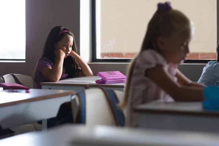 Elementary schoolgirls studying at desk in classroom. Signs of trauma in students concept