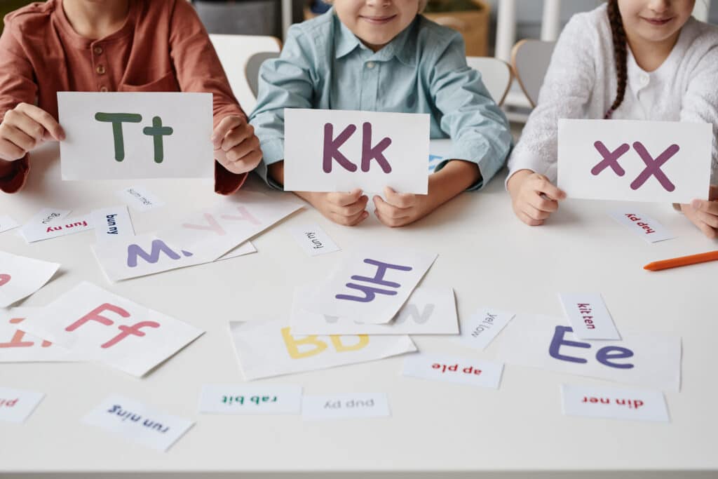 Close-up of group of children playing with letter cards phonics decoding concept