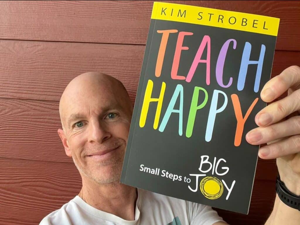 Dave Burgess holding a Teach Happy book.