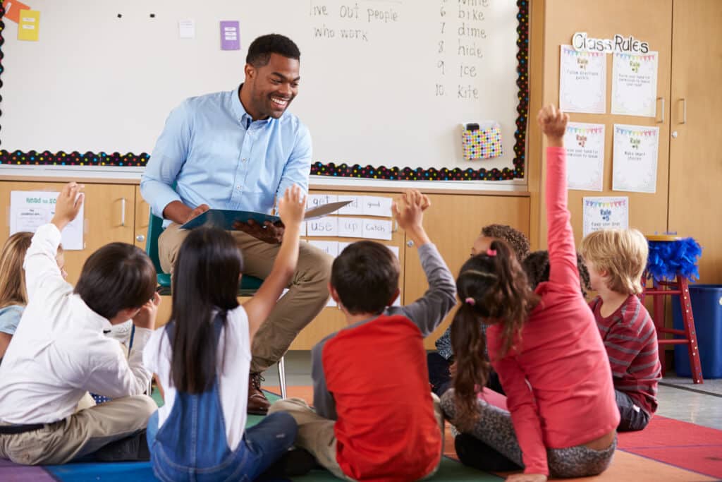 Elementary school kids sitting around teacher in a classroom - nature of happiness concept