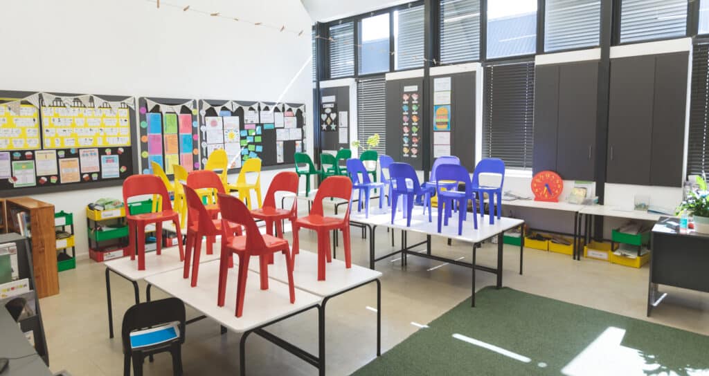 Front view of color chairs arranged on table in empty classroom at school