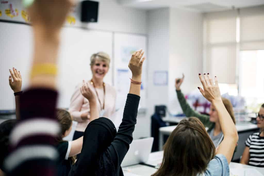 Group of students learning from a happy teacher