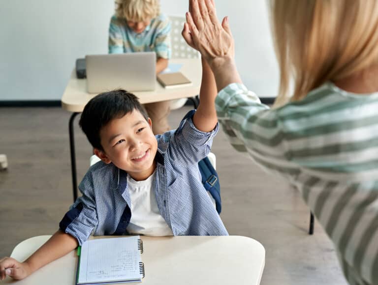 Happy Asian boy giving high five to female teacher at class in classroom gratitude concept