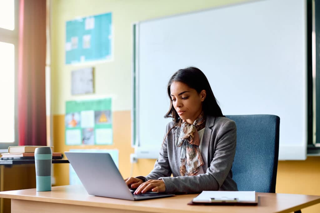 Hispanic female principal using laptop at her desk.