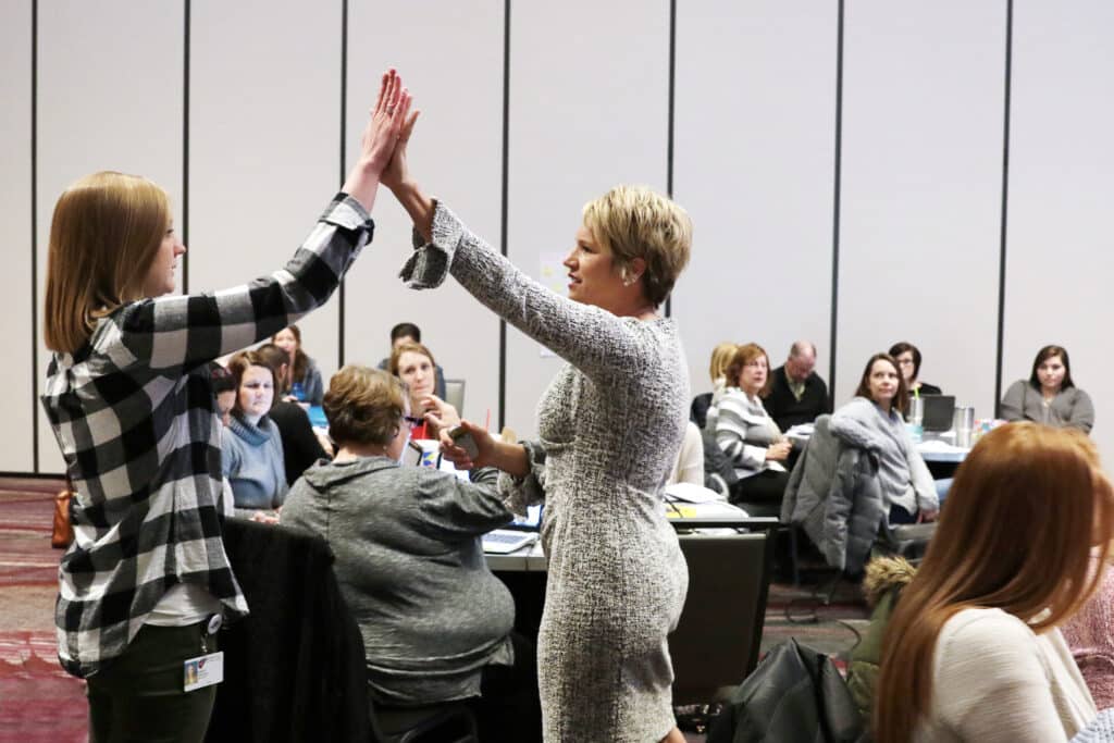 Kim Strobel giving a teacher high 5 at PD training