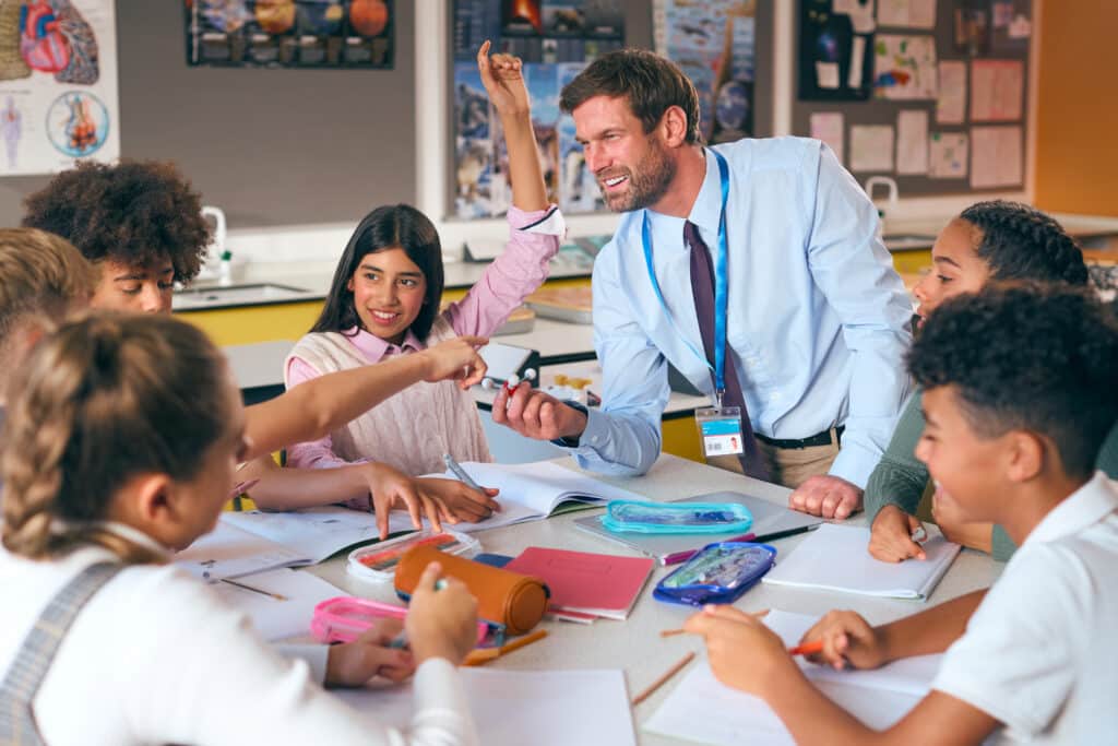 Male teacher sitting with students and smiling