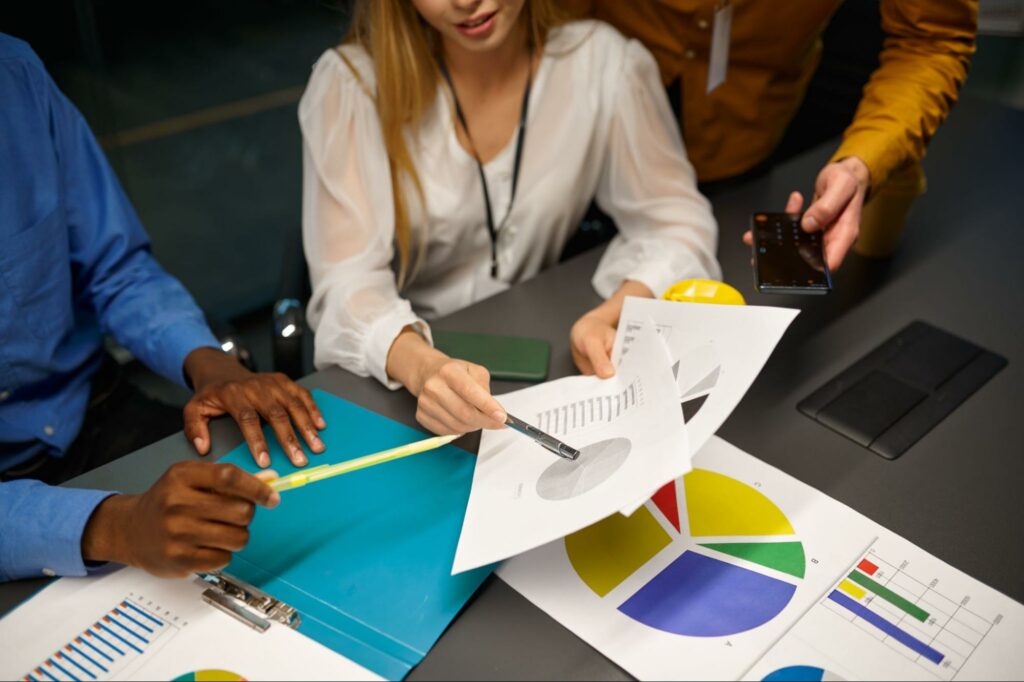 Team collaborating on data analysis with charts and documents in a meeting.