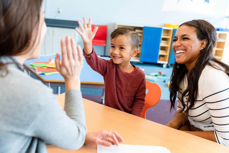 teacher gives boy high five at one of their parent-teacher conferences
