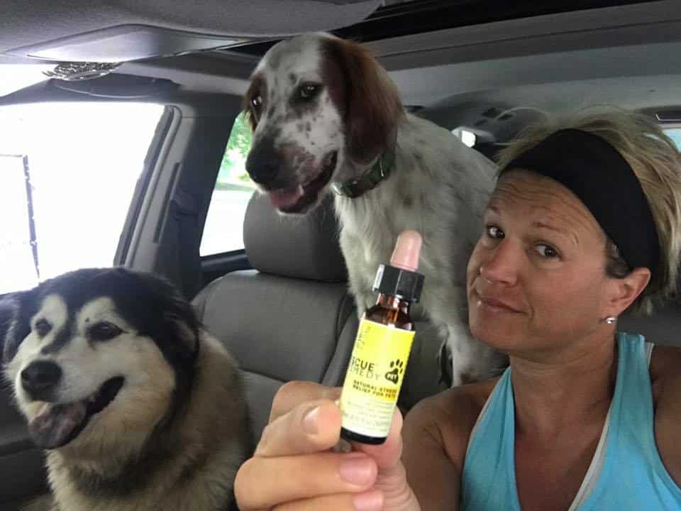 Image of two dogs and woman displaying bottle of Rescue Remedy