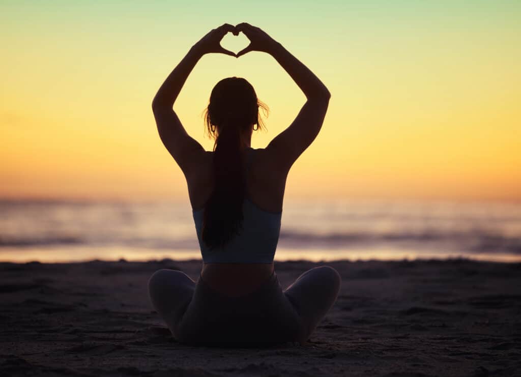 positive psychology concept with female doing yoga on the beach
