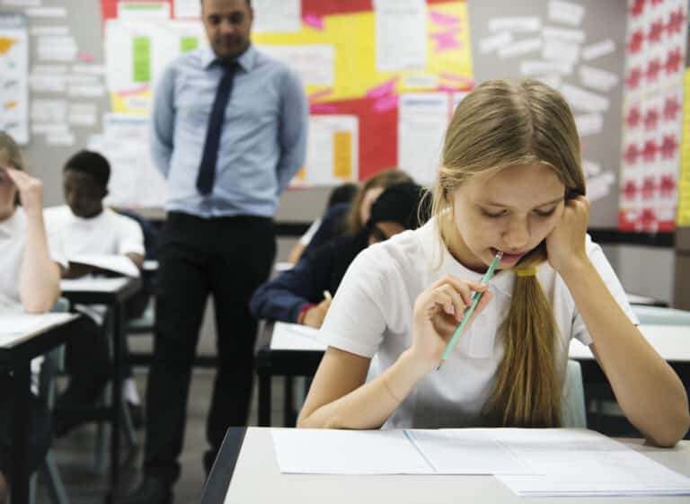 Students doing an exam in a classroom with a teacher monitoring
