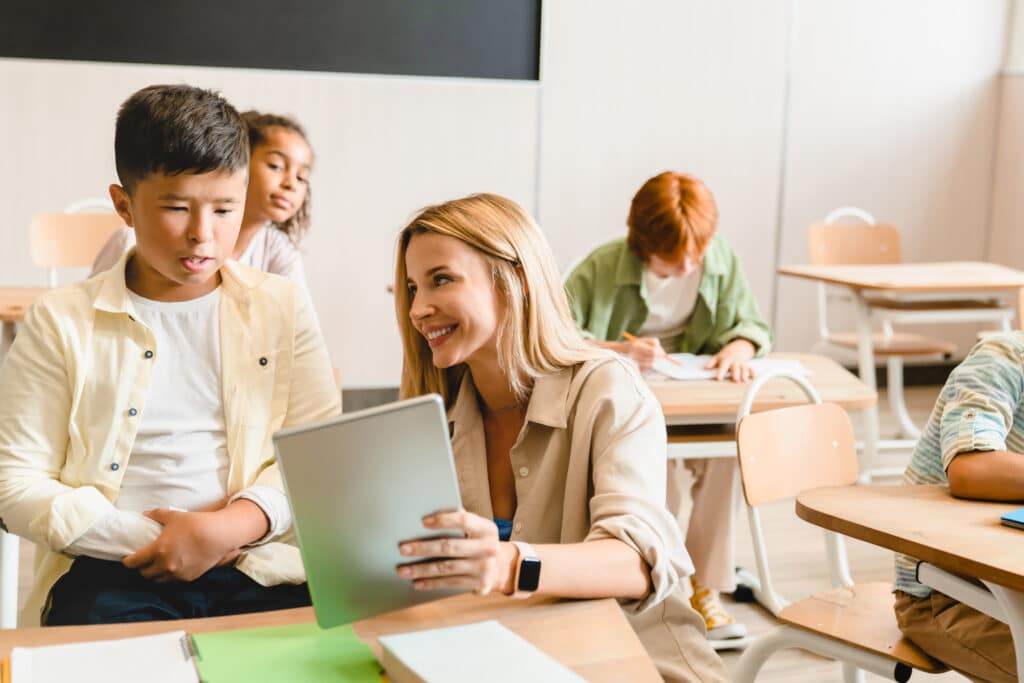 Young teacher helping her students with homework task