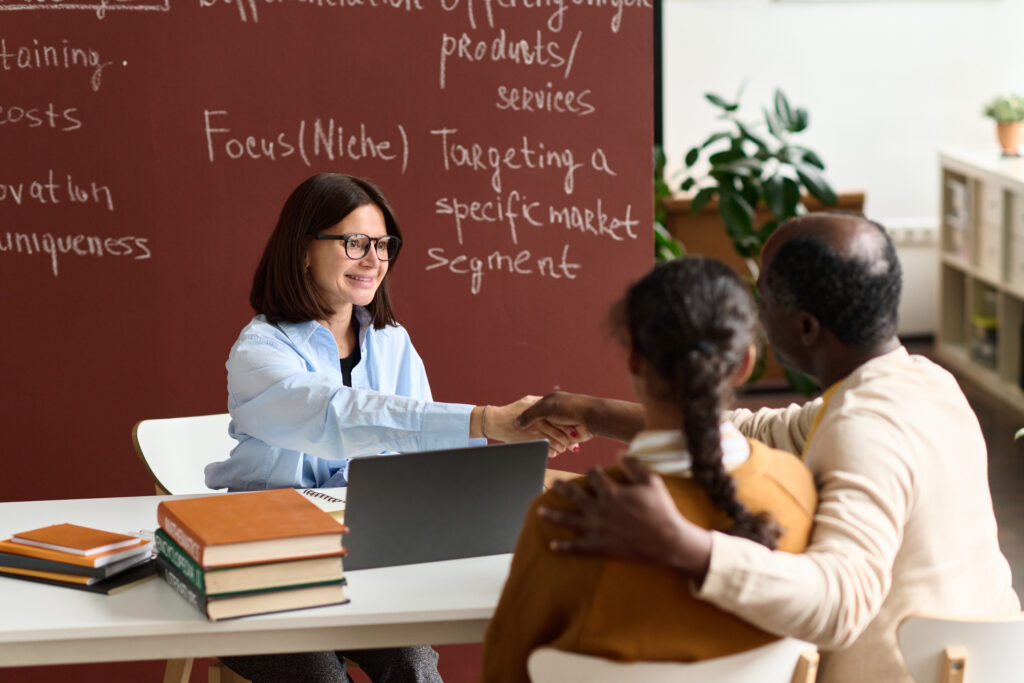 Teacher shaking hands with parent at parent-teacher conference