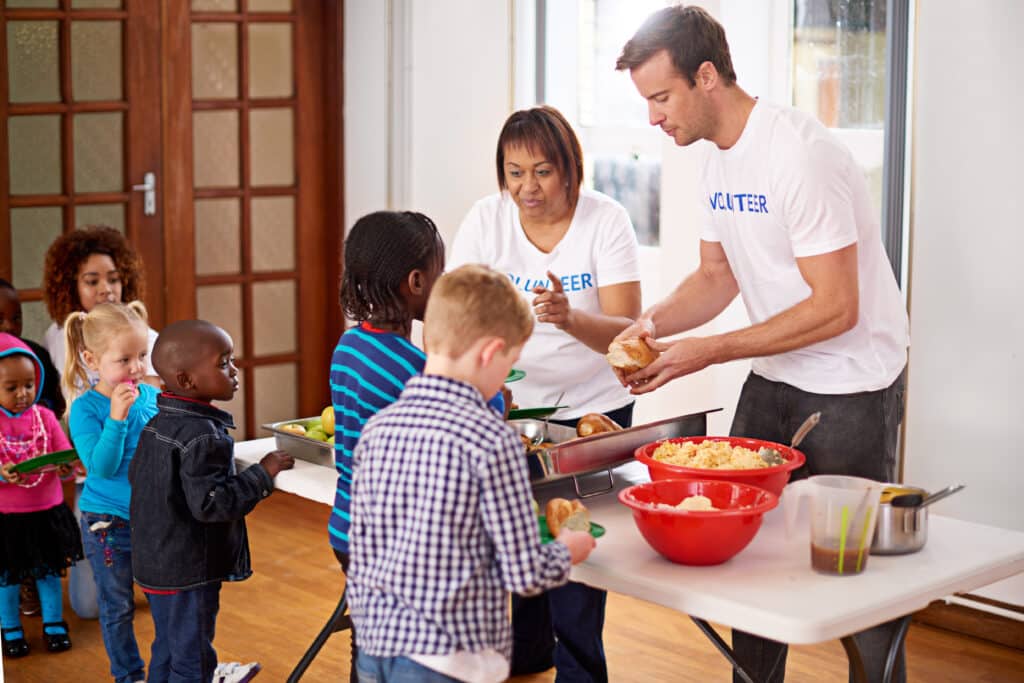 Volunteer parents serving food to a group of students at a school event