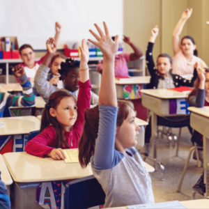 students in the classroom raising their hands to answer a question