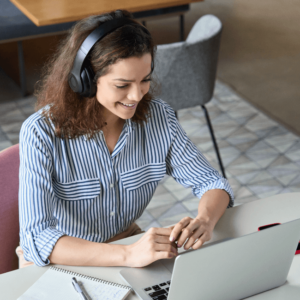 woman with headphone smiling in front of her laptop