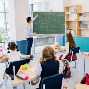 Teacher writing on the board with students sitting on their chair