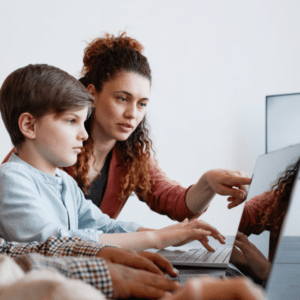 Teacher teaching student how to navigate the laptop.