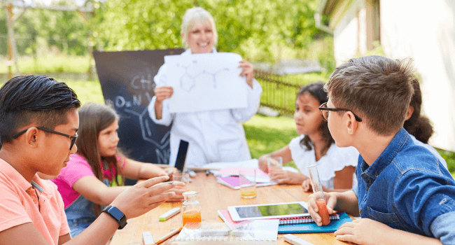 Teacher with students studying outside.